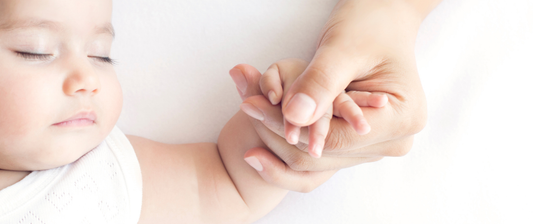 baby sleeping and holding parents hand