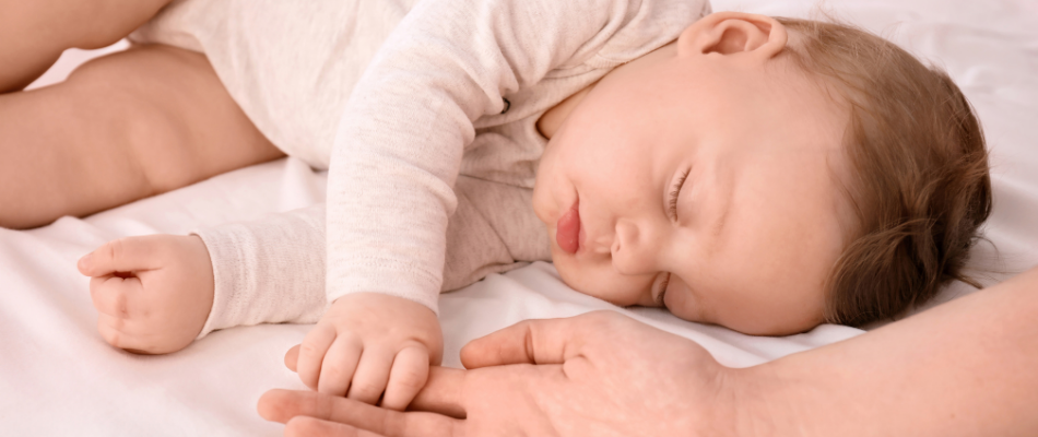 baby asleep holding parent's hand